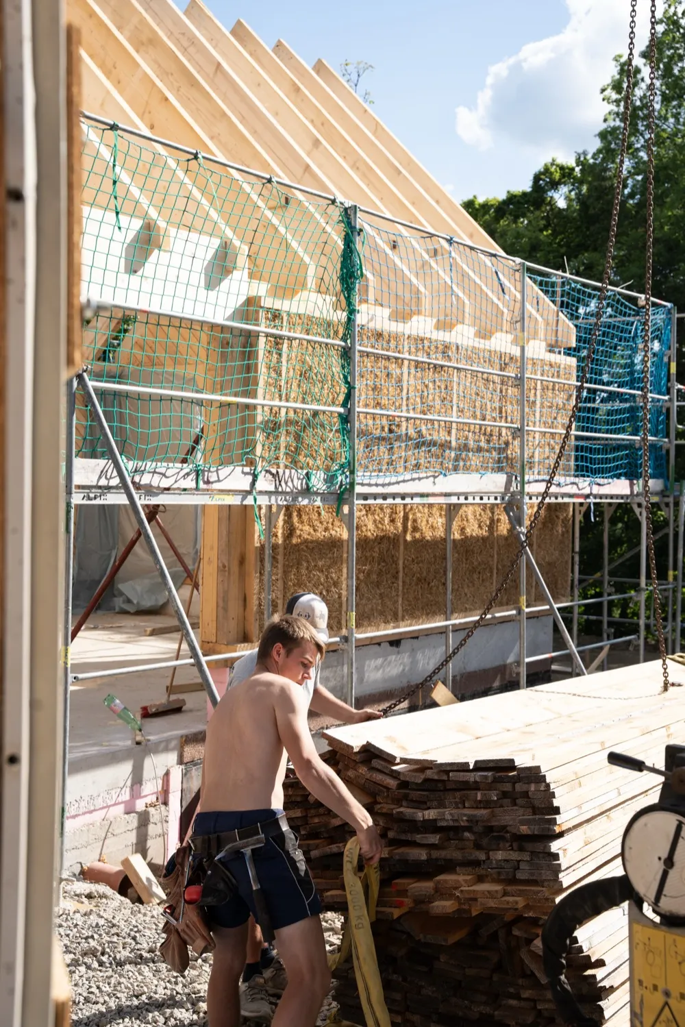 Strohballen werden von Hand in ein Holz-Fachwerk eingebracht, Strohballenbau in der Steiermark