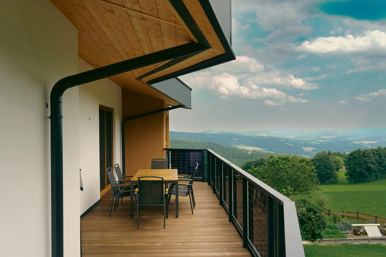 Haus Anita: Balkon mit Holzboden und Esstisch, dahinter der weite Blick über das Tal