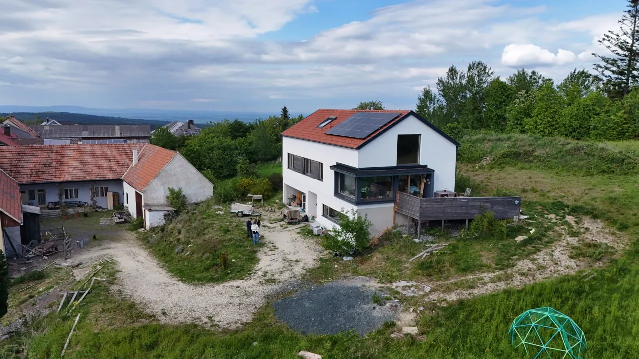 Haus Antonia: Luftbild des Hauses am Hang, links ein Bauernhof, im Hintergrund die Hügellandschaft