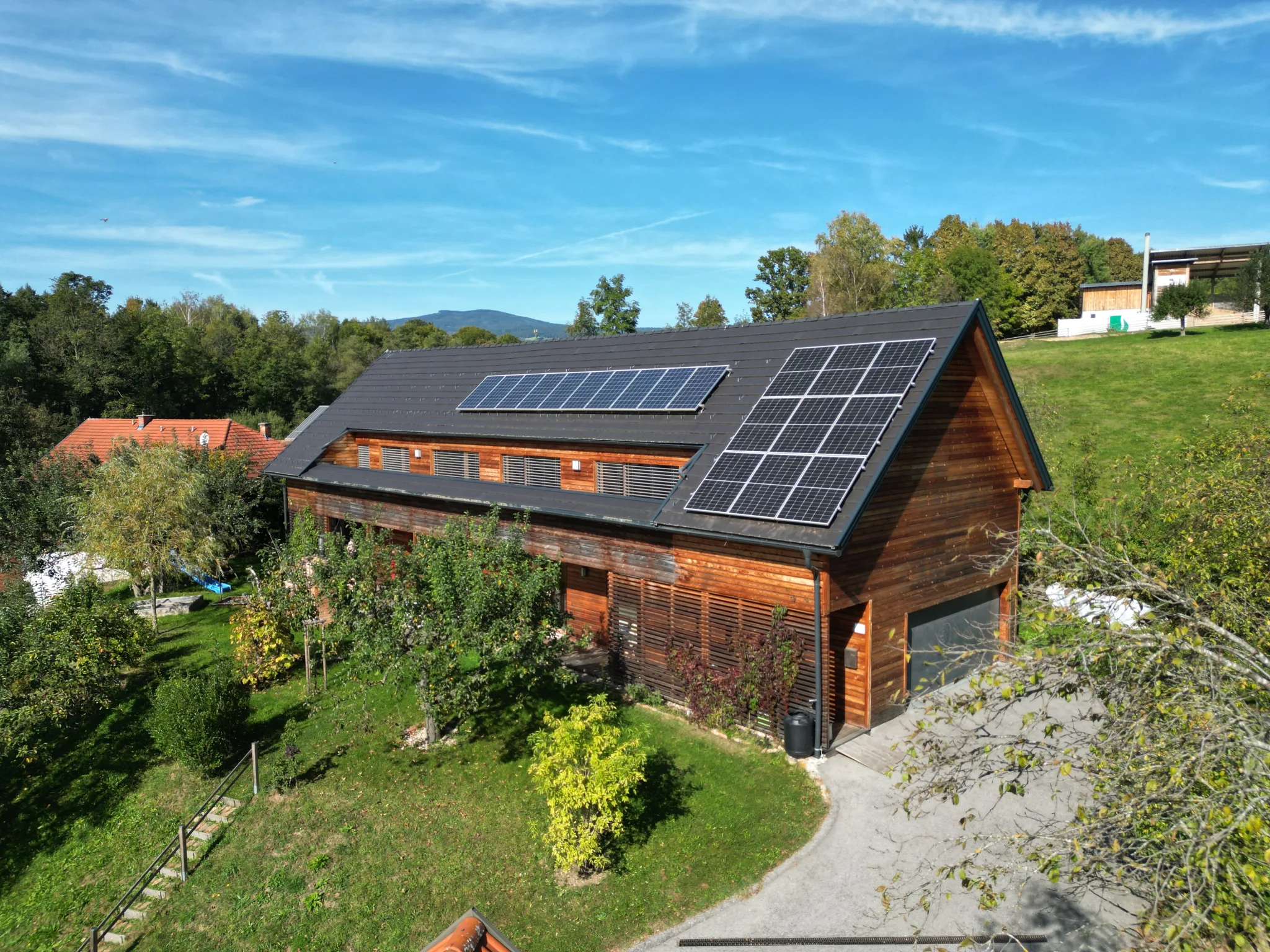 Haus Monika: Drohnenaufnahme des Holzhauses mit Photovoltaikanlage am Dach