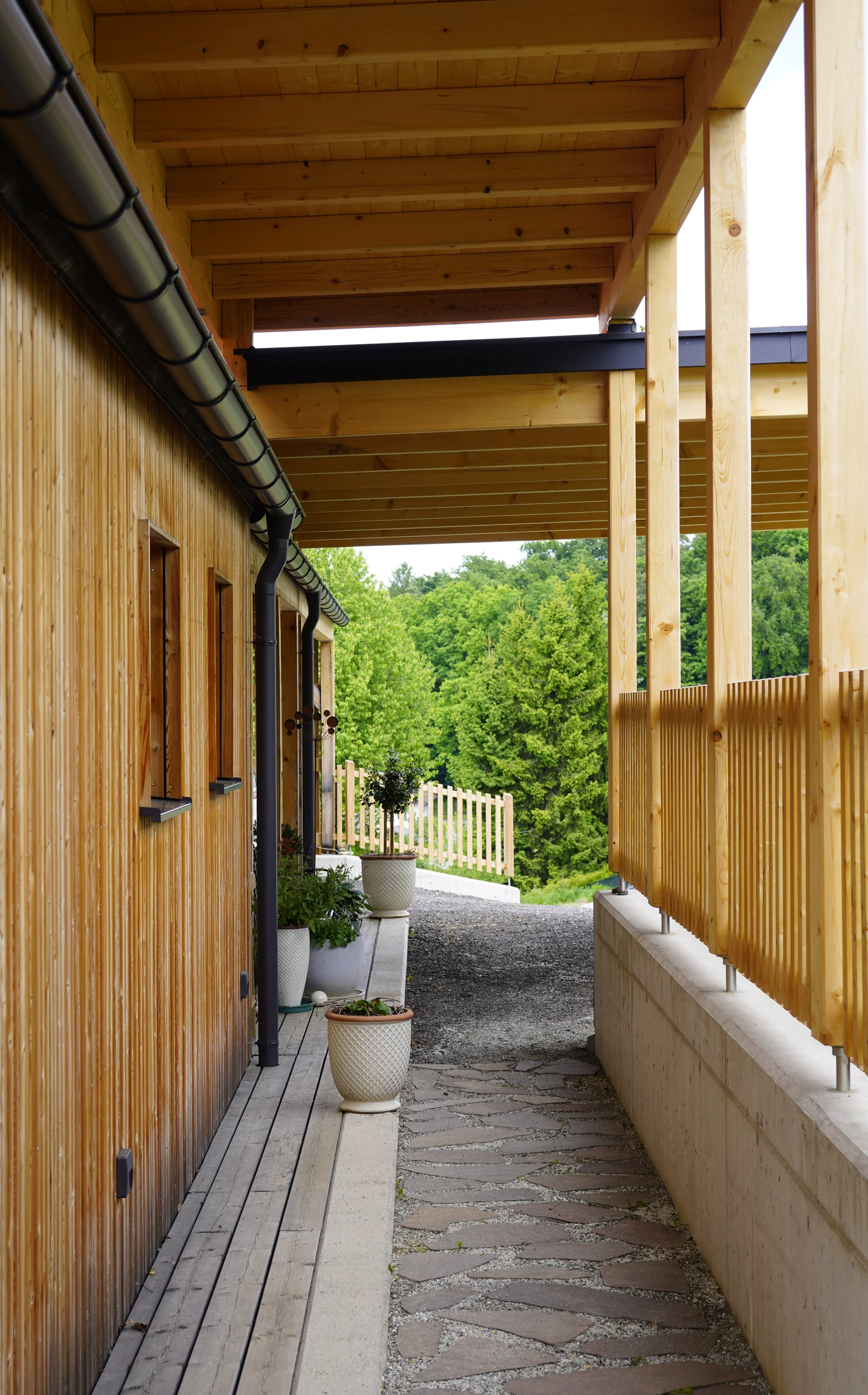 Haus Renate: Überdachter Durchgang mit Holzschalung und Natursteinpflaster