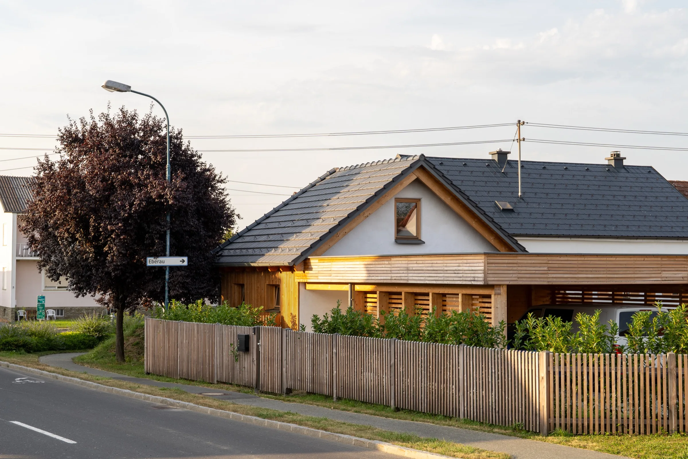 Haus Teresa: Straßenansicht mit dem neuen Zubau in Holzbauweise im Abendlicht
