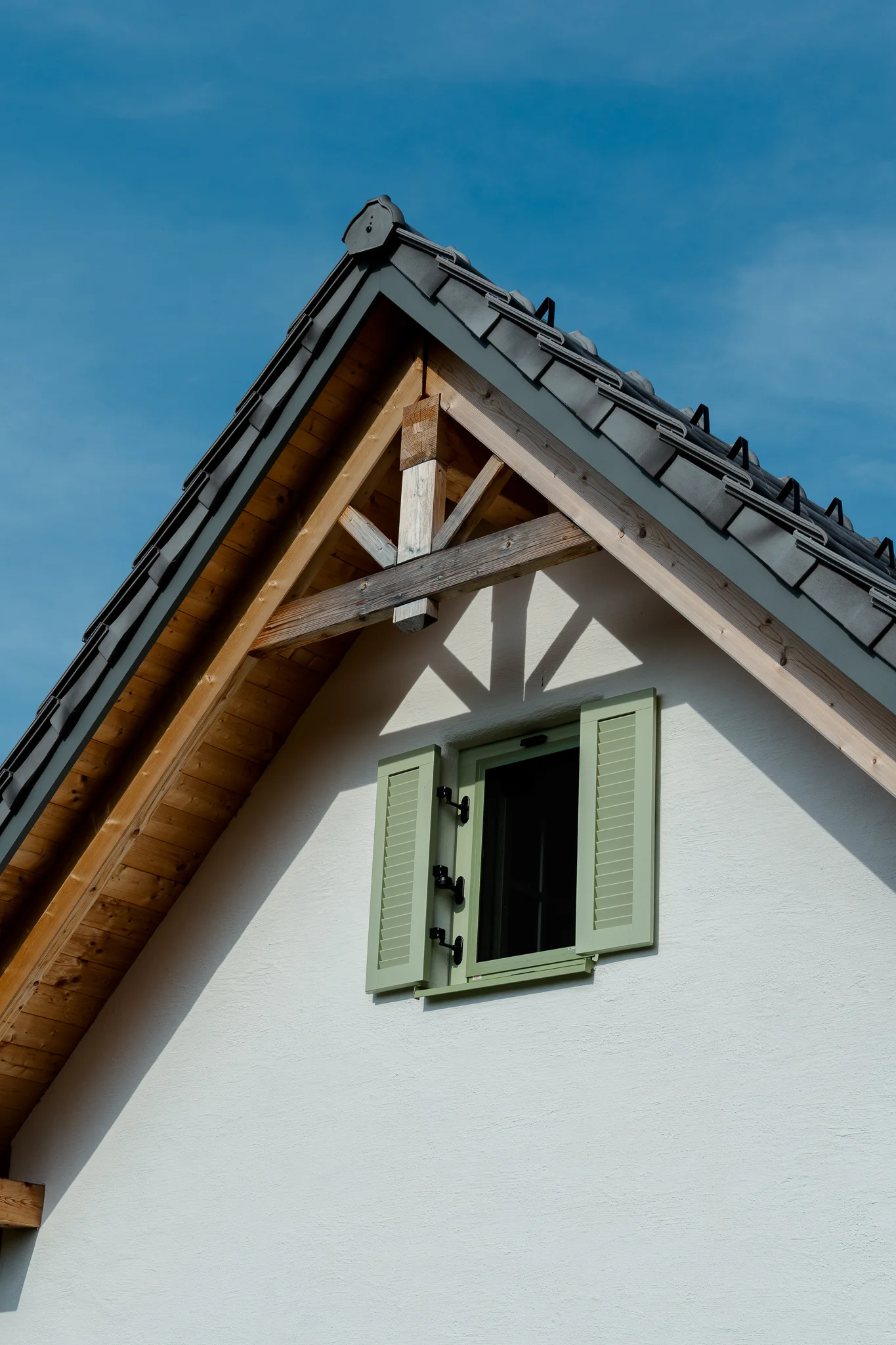 Kellerstöckl: Detailansicht des Dachgiebels mit sichtbarer Holzkonstruktion und grünen Fensterläden