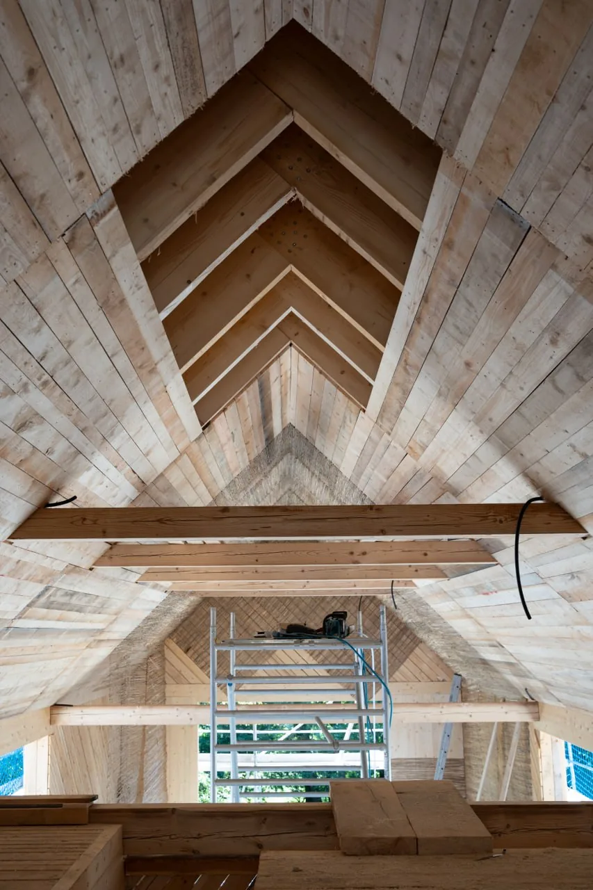 Projekt Lauber: Blick von unten in die Dachkonstruktion aus sichtbarem Holz mit gefalteter Untersicht