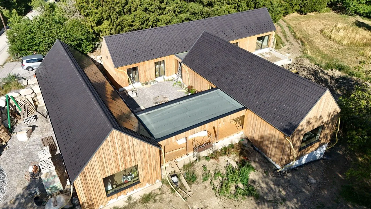 Projekt Lauber: Luftaufnahme der drei Baukörper mit fertiger Holzfassade, dazwischen der Hof