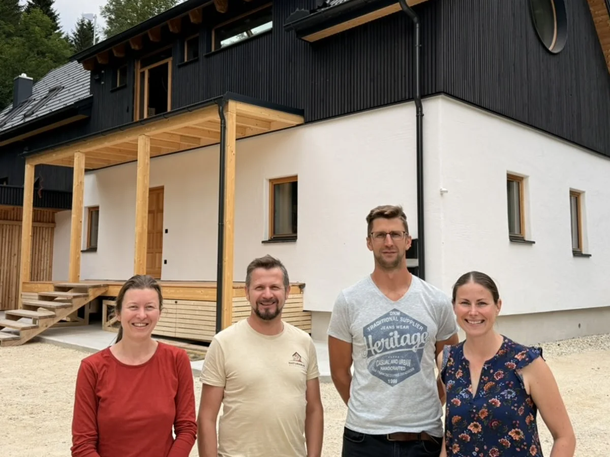 Vier Personen des Naturhaus-Wechselland-Teams vor einem fertigen Haus mit dunkler Holzfassade und Veranda