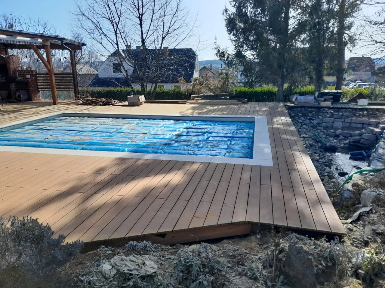 Holzterrasse, die um einen Pool herum geführt ist, mit umlaufendem Belag aus Massivholzdielen