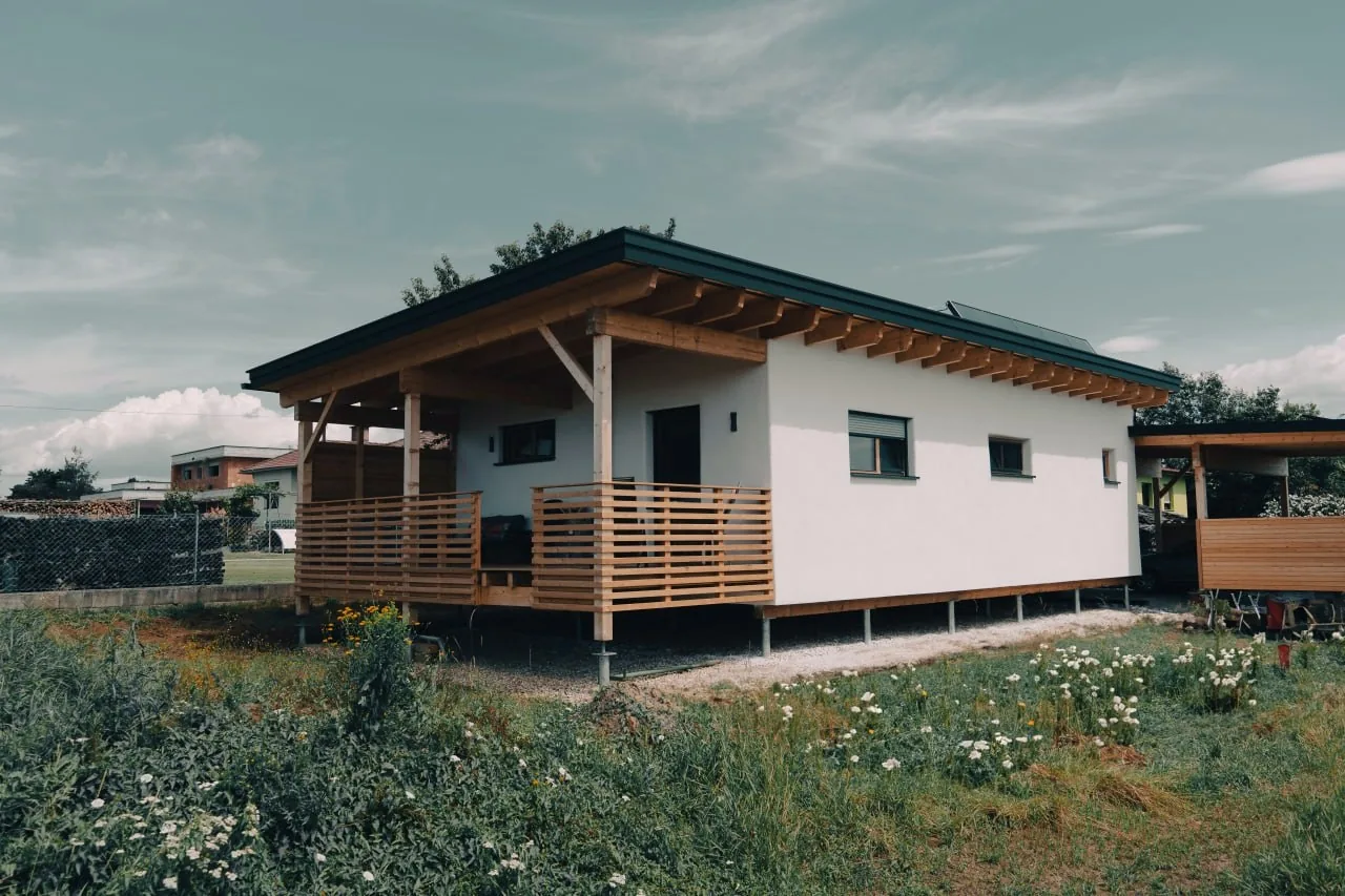 Tinyhaus Martina: Das Haus steht auf schlanken Schraubfundamenten über einer Blumenwiese, davor die überdachte Holzterrasse