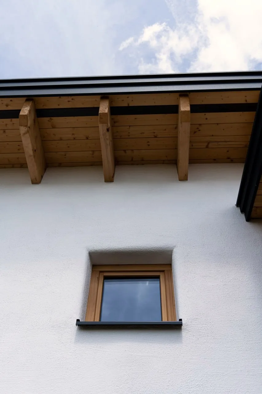 Tinyhaus Martina: Blick von unten auf den Dachüberstand mit sichtbaren Holzsparren über der weißen Fassade