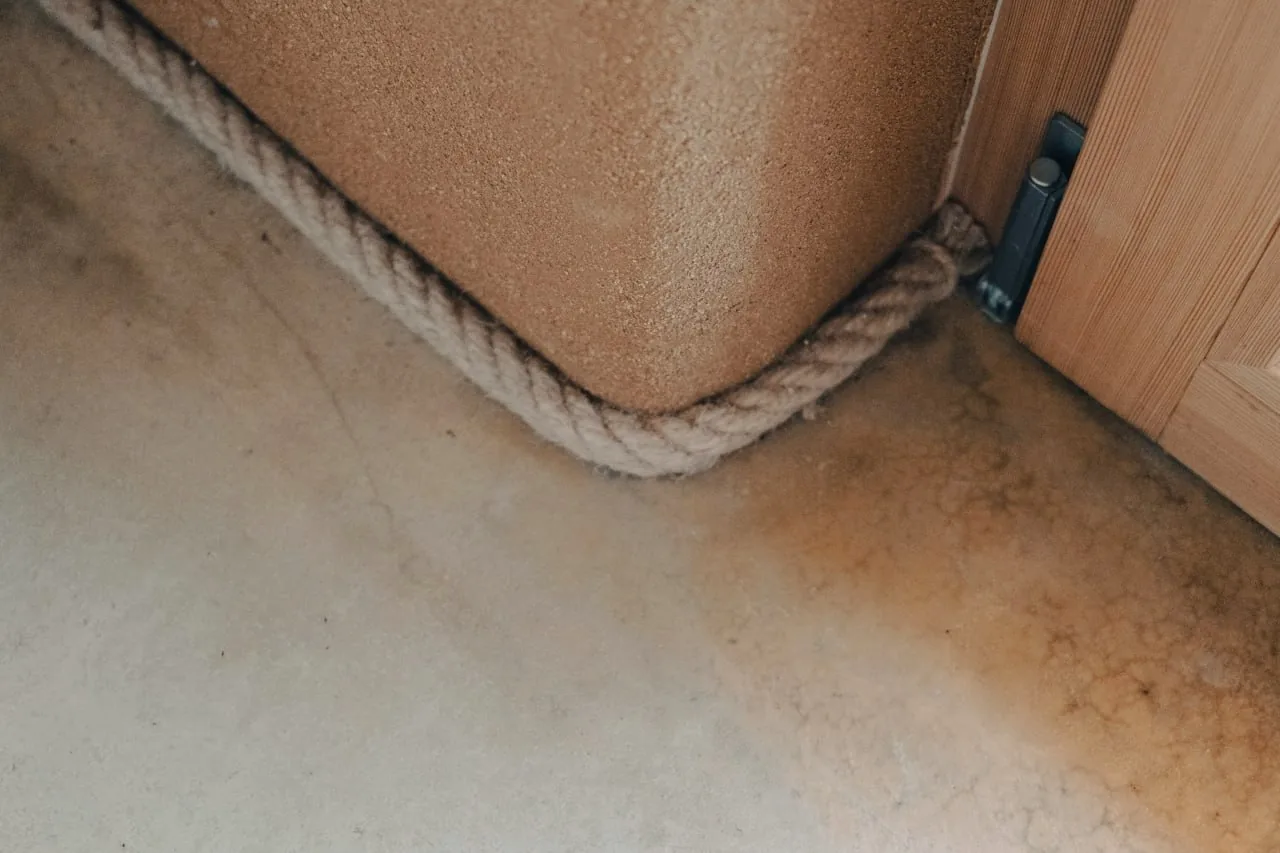 Tinyhaus Martina: Detail einer Raumecke, Lehmputzwand mit Seil als Sockelabschluss auf geschliffenem Estrich